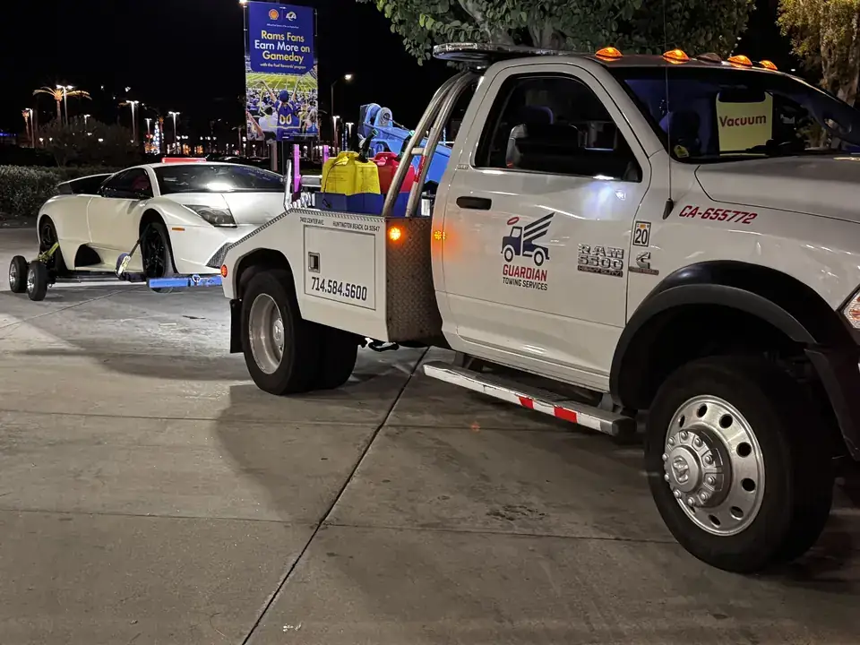 Guardian Towing tow truck loading a white Lamborghini at night in Huntington Beach