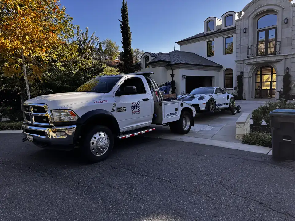 Guardian Towing tow truck towing a white Porsche 911 GT3 RS from a private driveway