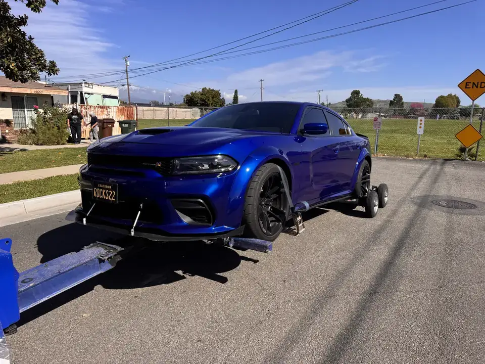 Blue Dodge Charger Scat Pack Widebody loaded on wheel dollies