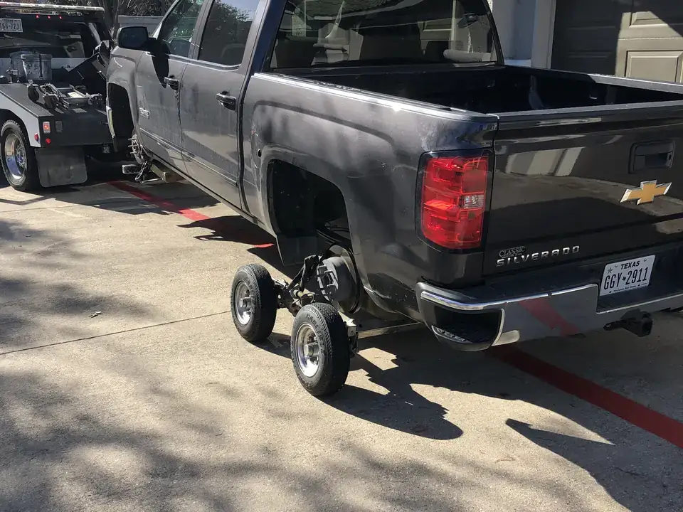 Chevrolet Silverado pickup lifted on wheel dollies in a residential driveway